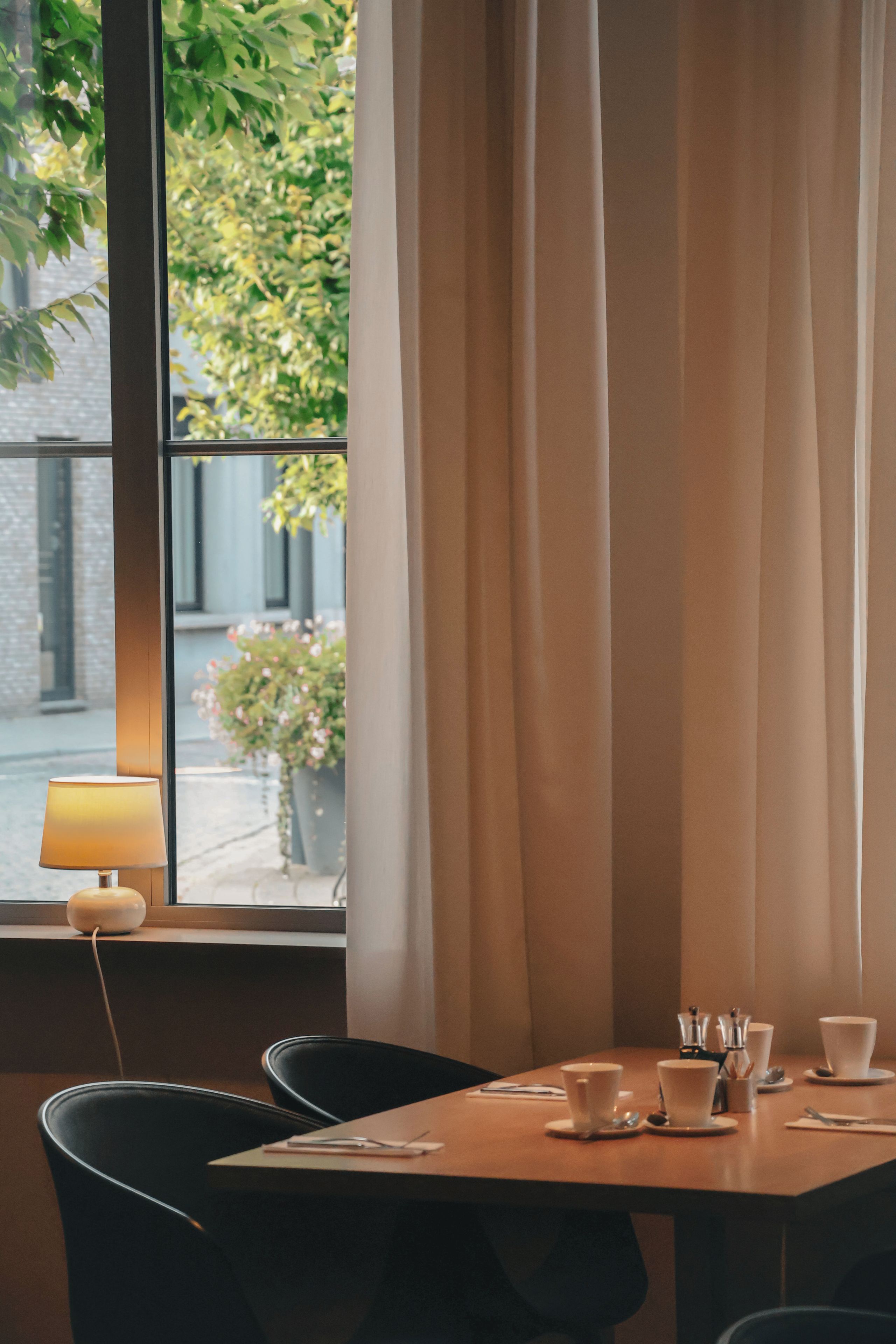 Een eettafel met lamp, stoelen en uitzicht op groen.