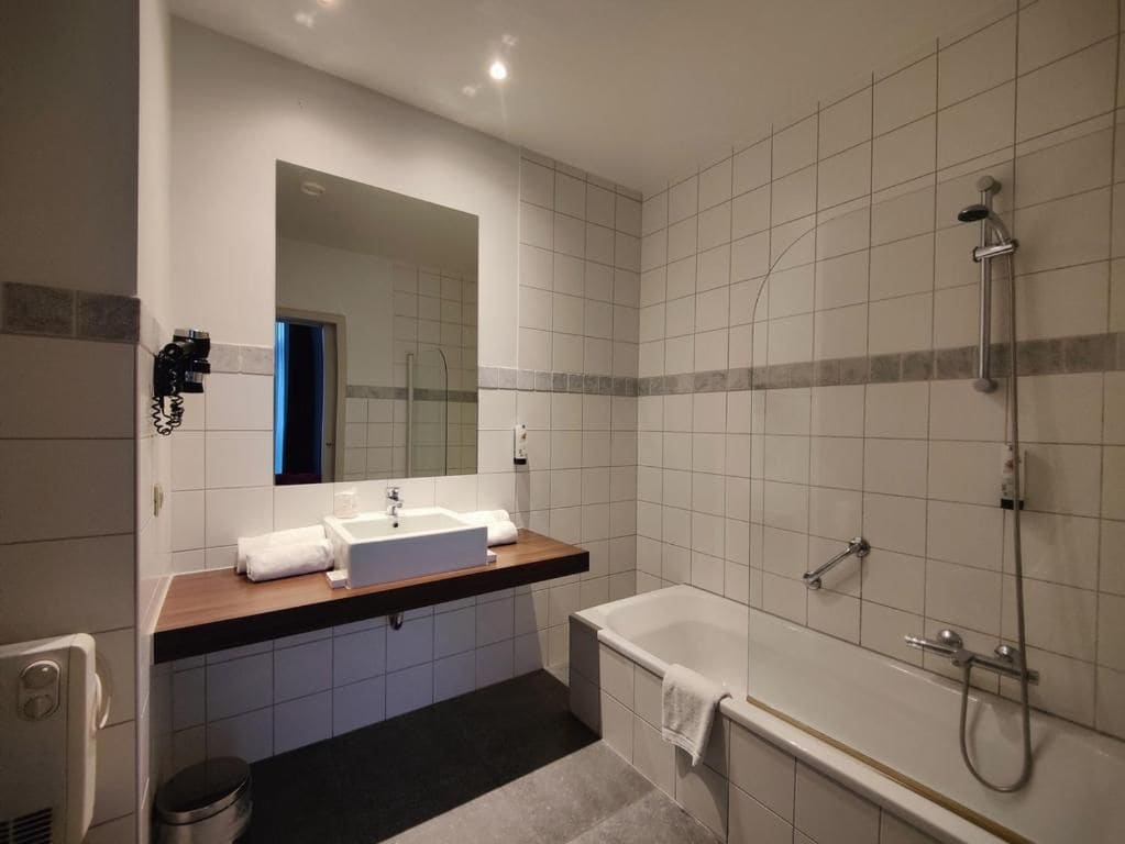 Une salle de bain moderne équipée d’une baignoire, d’une douche et d’un lavabo avec un miroir au-dessus.