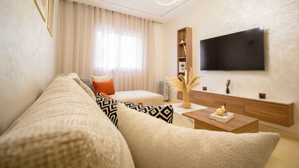 Un salon moderne comprenant un canapé, une table basse, un téléviseur et des objets de décoration.