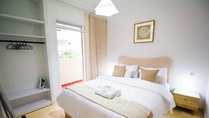 Une chambre d’hôtel comprenant un lit, une table de chevet, une armoire et une porte donnant sur un balcon.