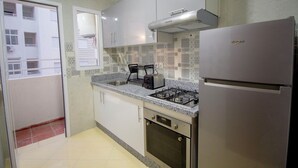 Une cuisine équipée d’une cuisinière à gaz, d’un four encastré, d’un réfrigérateur et d’une fenêtre.