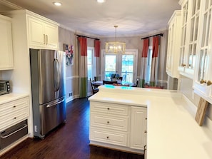 A kitchen with white cabinetry, a stainless steel refrigerator, and a dining area with a table and chairs. - Spacious Augusta Masters Rental-Quiet Cul-de-Sac Home less than 5 miles to ANGC (Martinez)