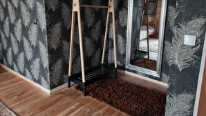 Una habitación con piso de madera, papel tapiz blanco y negro a cuadros, un columpio de madera, alfombra blanco y negro a cuadros y un espejo con marco negro.