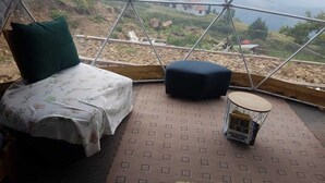 Una habitación con tienda de campaña, una cama, un almohadón, una mesita y vistas a un paisaje.