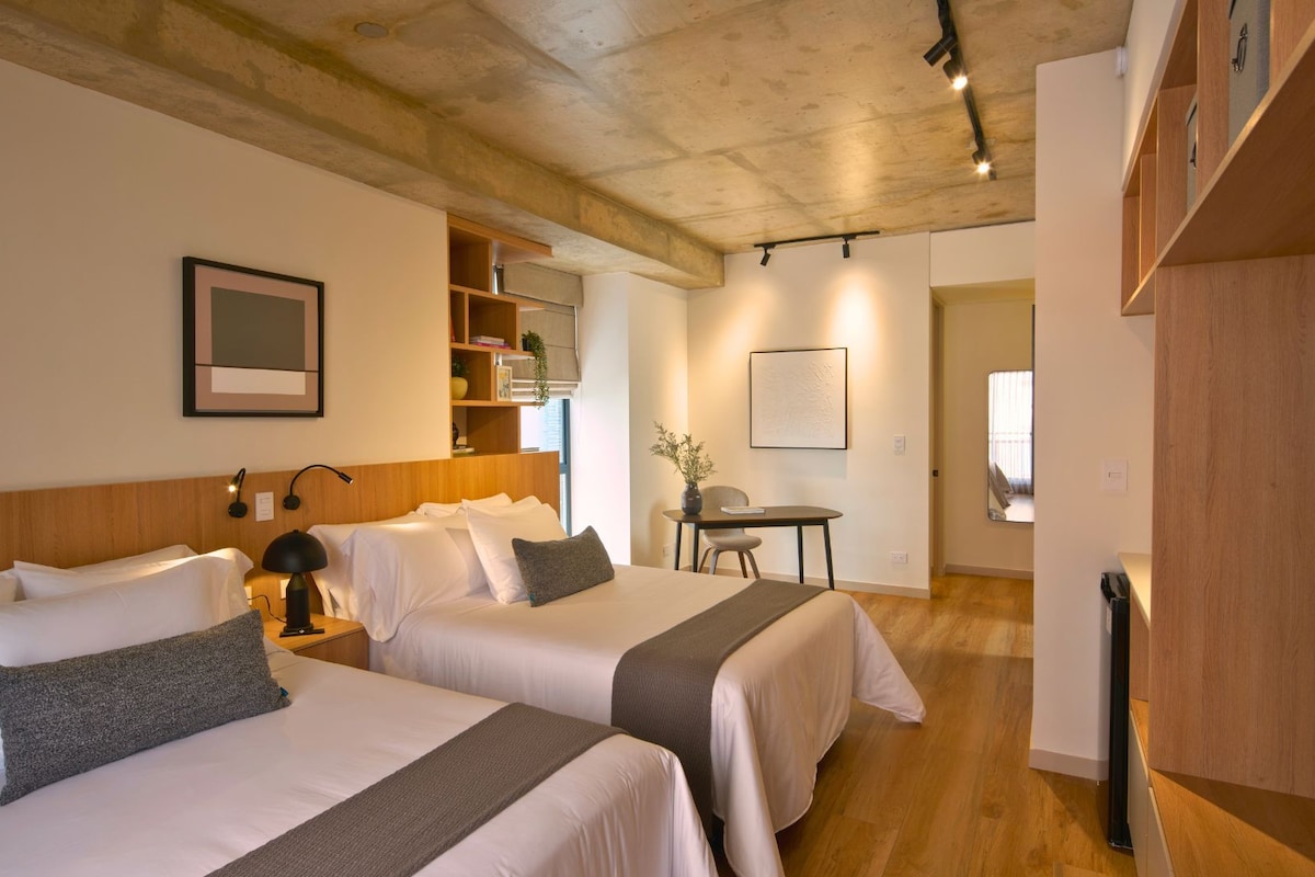 A hotel room with two beds, a desk, and a chair.