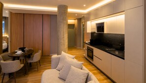 Una cocina moderna con horno empotrado y microondas, un comedor con una mesa redonda y sillas, y un pilar grande en el centro.