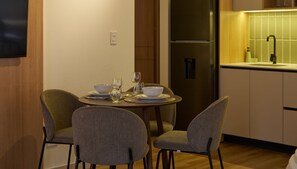 A modern kitchen with a dining area, including a table set for two with chairs, a refrigerator, and a sink. - Kubik Living 8i8 (Bogota)