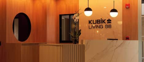 A reception desk with a marble top, wooden paneling on the walls, and two pendant lights.