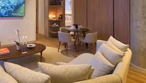 Una sala de estar moderna con un sofá, una mesa de centro y un comedor con sillas y una mesa dispuesta para dos.