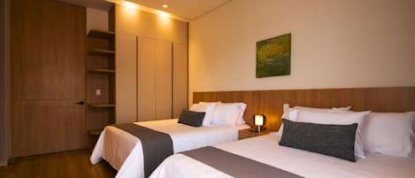 Habitación de hotel con dos camas, un armario, un cuadro en la pared y una mesita de noche con lámpara.
