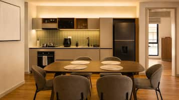 Una cocina moderna con comedor, que incluye una mesa grande con seis sillas, horno empotrado y refrigerador.