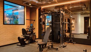 A gym with exercise equipment, a mirror, and a large window. - Kubik Living 8i8 (Bogota)