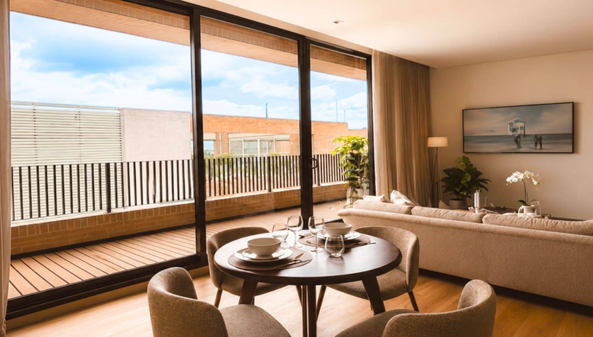 A modern living room with a round dining table, comfortable seating, a sofa, and a large window offering a view of a building and sky.
