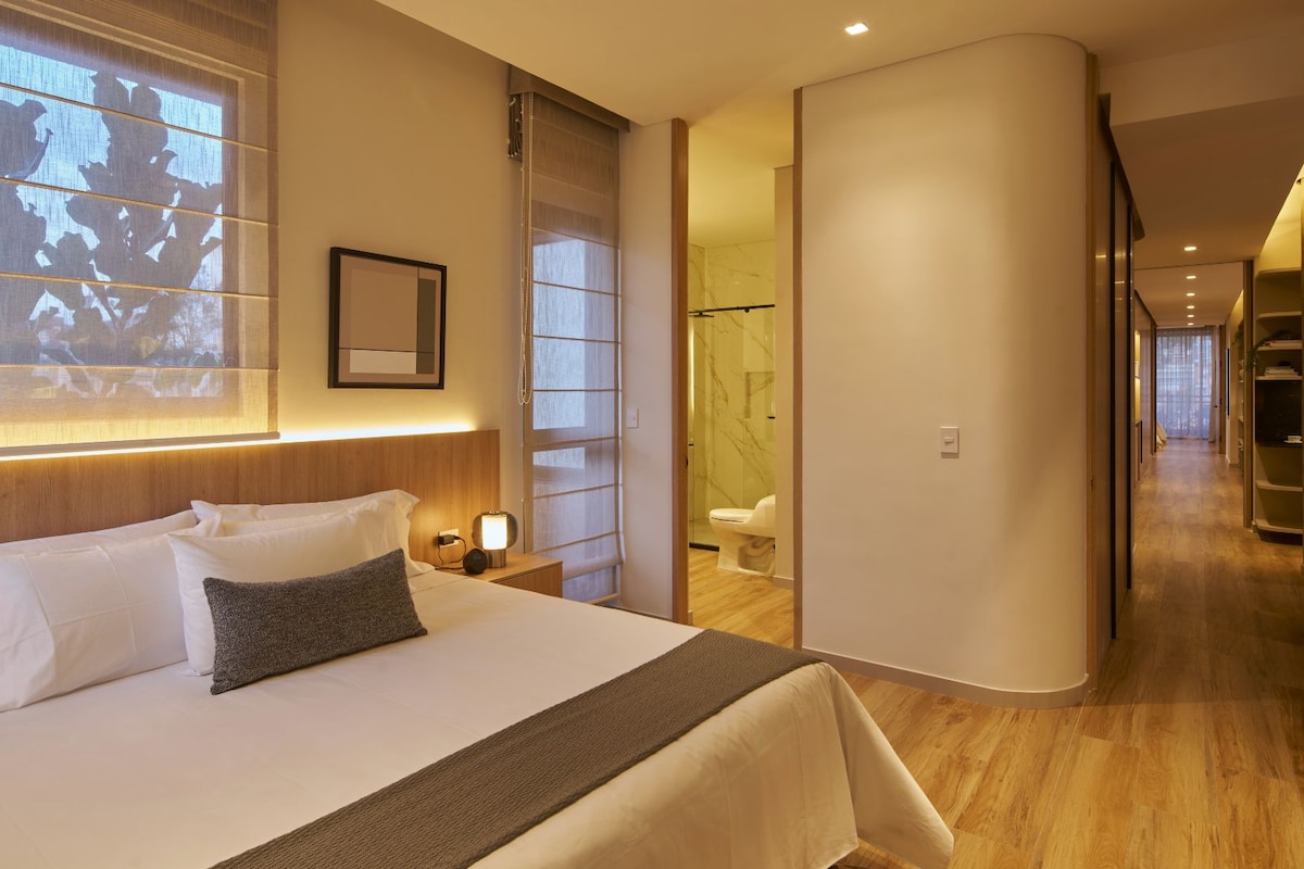 A hotel room with a bed, bedside table, and a large window with a projection.