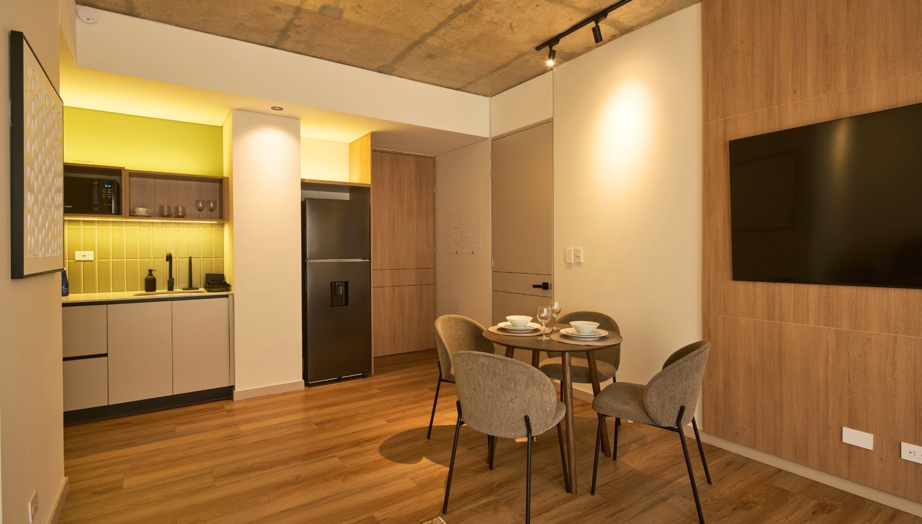 Una cocina moderna con refrigerador empotrado, armarios de madera y un comedor con mesa y sillas.