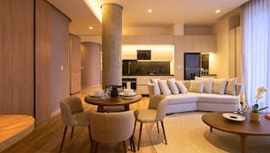 Una sala moderna con sofá, sillas, una mesa de comedor y una cocina al fondo.