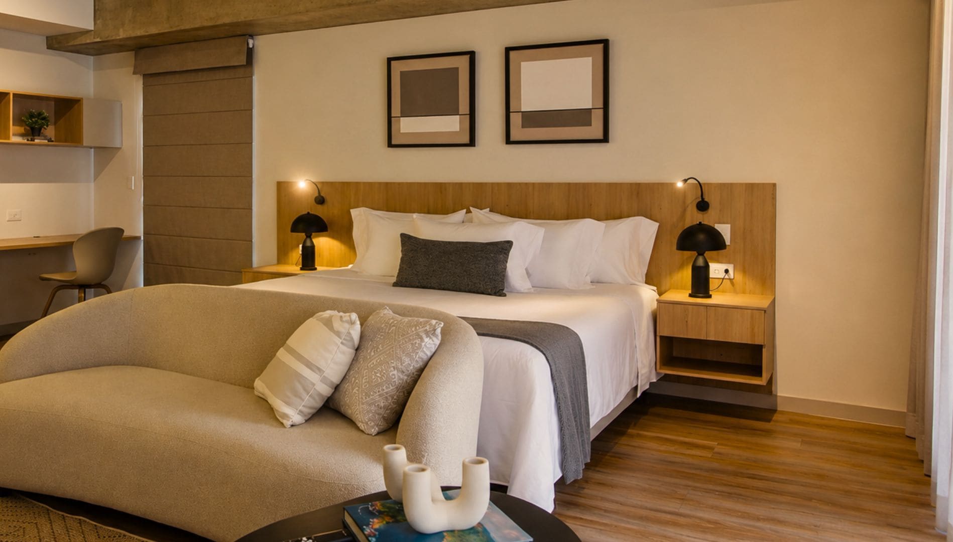Une chambre d’hôtel comprenant un lit, des tables de chevet, un bureau, une chaise et un canapé.