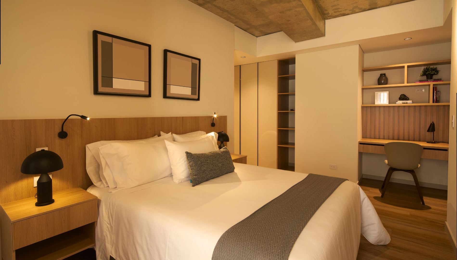 A hotel room with a bed, bedside lamps, a desk, and a chair.