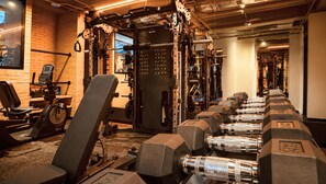 A gym with various exercise equipment including a treadmill, weight bench, and dumbbells. - Kubik Living 8i8 (Bogota)
