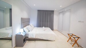 Un dormitorio moderno con cama, mesita de noche y espejo.