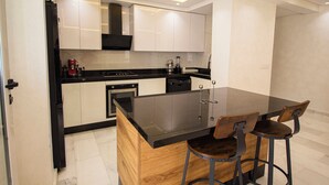 A modern kitchen with a central island, bar stools, and built-in appliances. - Luxury 2-Bedroom Pool, Quiet & Spacious (Tanger)