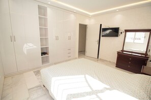 A bedroom with a bed, a wardrobe, a dresser, a television, and a mirror. - Luxury 2-Bedroom Pool, Quiet & Spacious (Tanger)