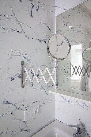 A bathroom with a marble wall, a mirror, a towel rack, and a sink. - Luxury 2-Bedroom Pool, Quiet & Spacious (Tanger)