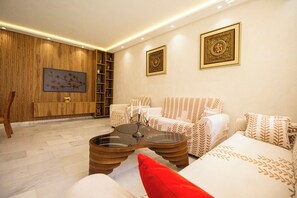 A modern living room with a sofa, armchairs, a coffee table, and decorative wall art. - Luxury 2-Bedroom Pool, Quiet & Spacious (Tanger)