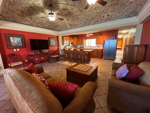 A spacious living room with a high ceiling, a dining area, and a kitchen with wooden cabinets. - Comfortable Beachfront Condo Las Palmas II 11 B (Puerto Peñasco)