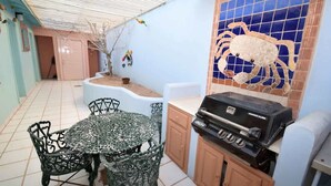 Eine Terrasse mit Grill, Tisch und Stühlen sowie eine Wand mit Kachelfliesen und einem Krabbenmotiv.