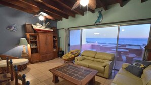Ein Wohnzimmer mit Meerblick, einem Holzkasten, einem Sofa, einem Couchtisch und einem Sessel.