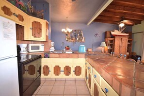 A kitchen with wooden cabinets, a microwave, a sink, and a blue kettle. - Beautiful Beachfront Condo Las Palmas II 3 (Puerto Peñasco)