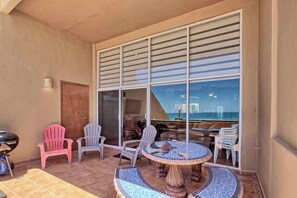Eine Terrasse mit einem runden Tisch, Stühlen und Blick aufs Meer.
