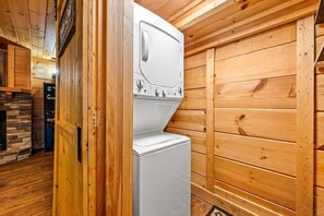 A laundry room with a washer and dryer, wooden walls, and a stone fireplace. - Cabin w/ 2 Hot Tubs · Theater · Game Room (Sevierville)