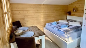 Ein kleines, gemütliches Zimmer mit einem Bett, einem Tisch mit Stühlen und einem Fenster.