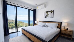 Une chambre à coucher moderne avec un grand lit, une vue sur l’extérieur et un tableau accroché au mur.