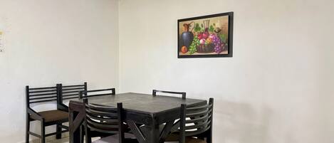 A dining area with a table and chairs, a tiled floor, a brick ceiling, and a painting on the wall.