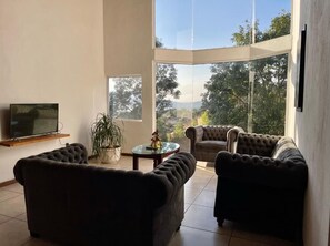 Ein modernes Wohnzimmer mit großem Fenster, Flachbildfernseher und zwei Sofas.