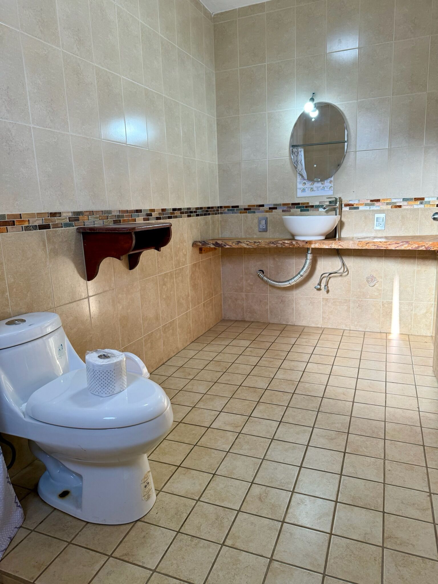 A bathroom with a toilet, sink, and tiled floor.