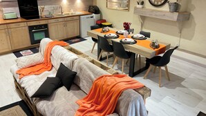 Een compacte leefruimte met een kitchenette, een eethoek en een bank met een plaid.