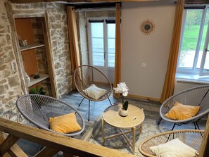 A room with stone walls, wicker chairs, a small table with a potted plant, and a view through a window. - Le Refuge du Revermont Cottage for 4 people (Cousance)