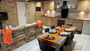 Een moderne keuken met houten kastjes, een inbouwoven en een eethoek met een houten tafel gedekt voor vier personen.