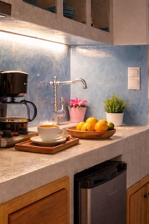A kitchen with a coffee maker, a bowl of fruit, and a potted plant. - Mistral Patmos (Patmos)