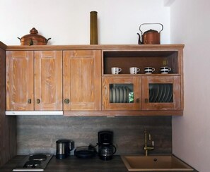 A kitchen with wooden cabinets, a stove, a coffee maker, and a sink. - Mistral Patmos (Patmos)