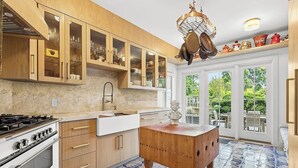Een keuken met houten kastjes, een gasfornuis, een spoelbak en een decoratieve houten tafel.