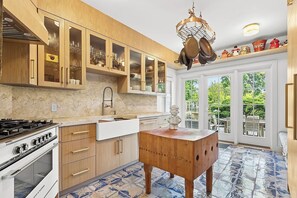 A kitchen with wooden cabinets, a gas stove, a sink, and a decorative wooden table. - Peaceful 4-bedroom house with AC in charming Bridgehampton (Bridgehampton)