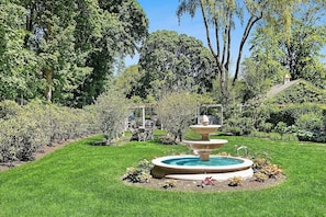A garden with a tiered fountain, lush greenery, and a clear sky. - Peaceful 4-bedroom house with AC in charming Bridgehampton (Bridgehampton)