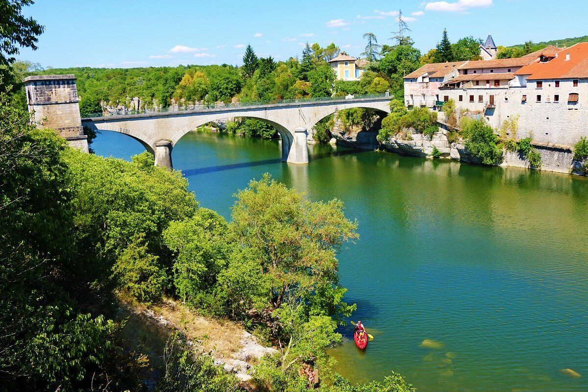 Un puente de piedra sobre un río, un kayak rojo y un edificio con tejado rojo.