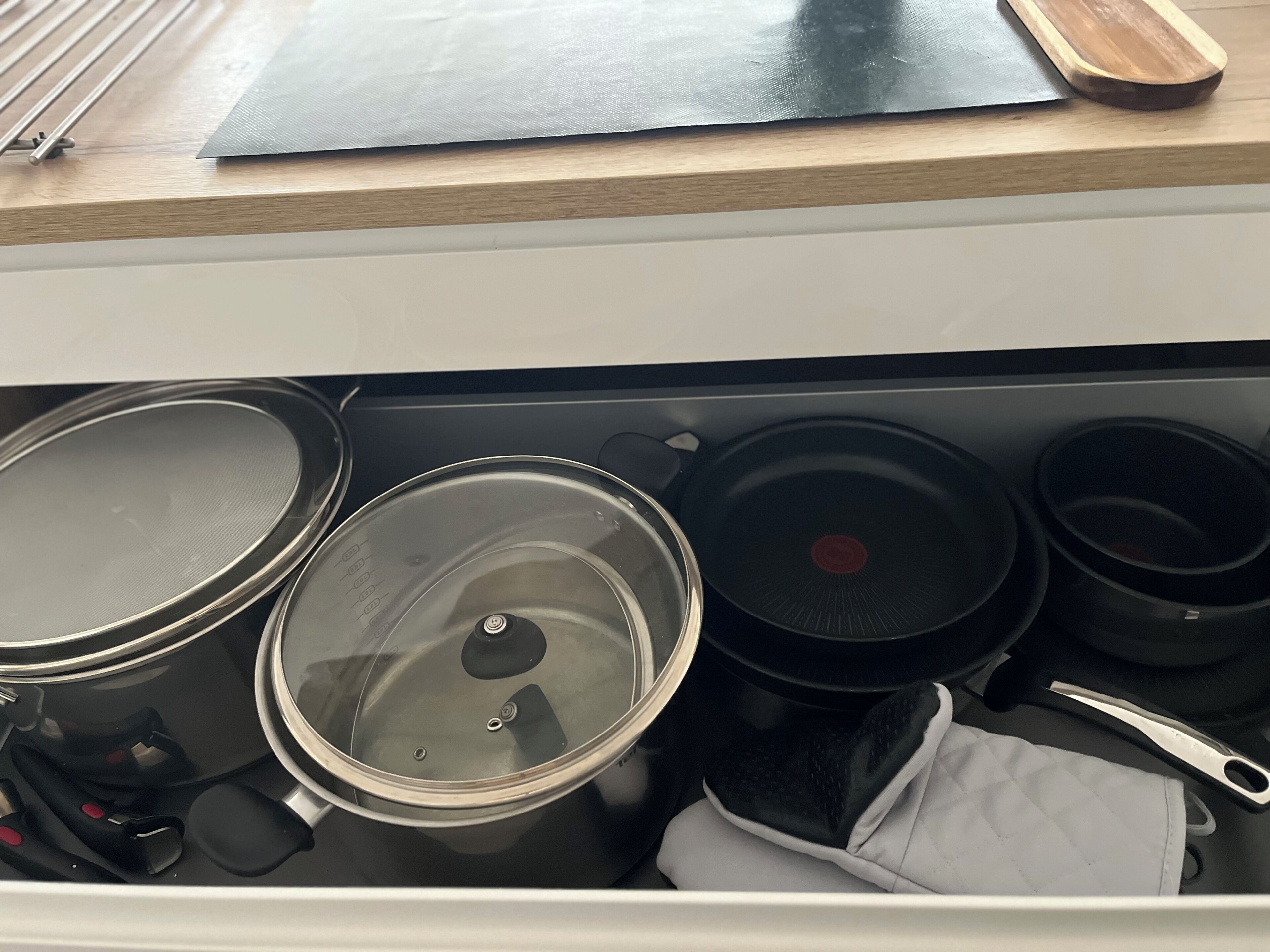 A kitchen drawer with pots, pans, and cooking utensils.