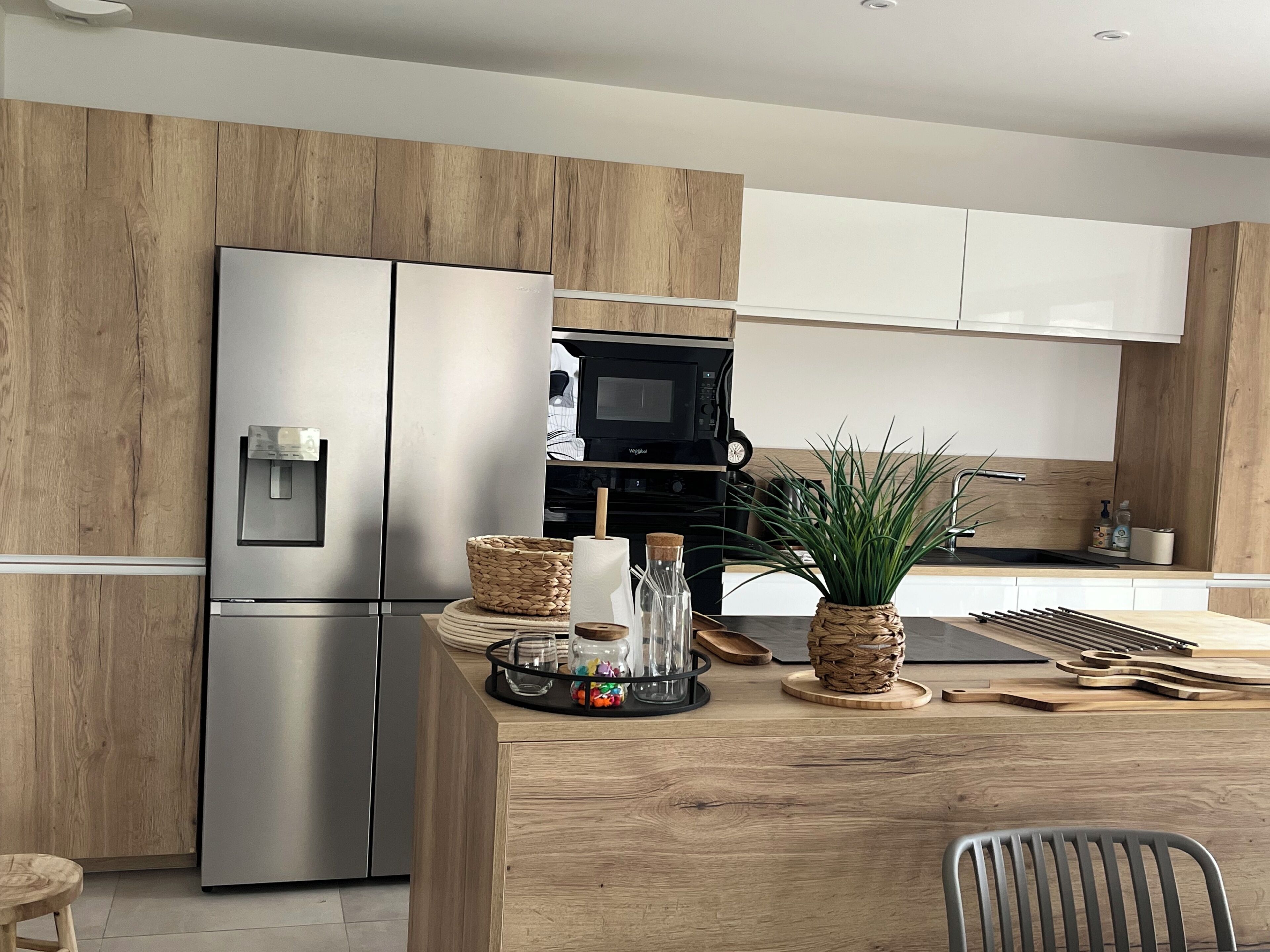 Une cuisine moderne dotée de meubles en bois, d’un réfrigérateur en acier inoxydable, d’un four à micro-ondes et d’un coin repas avec une table et des chaises en bois.
